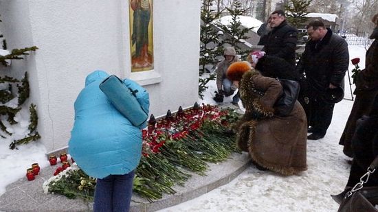 Люди кладут цветы у стены кафедрального собора Южно-Сахалинска